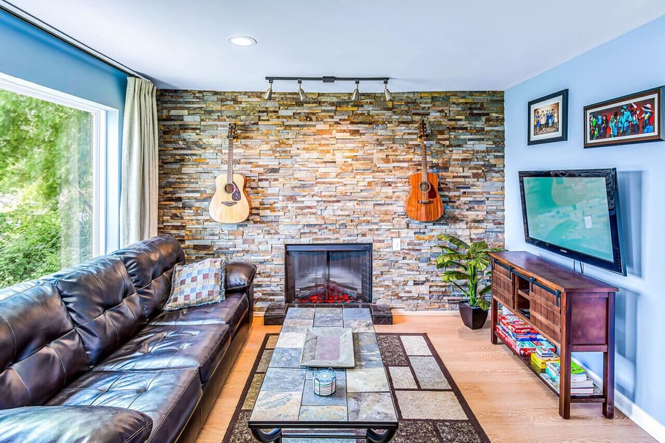Living room with a couch that turns into a sleeper sofa. Smart TV with YouTube TV for cable, guitars, electric fire place and a great view of the river! Private patio connected to this condo.