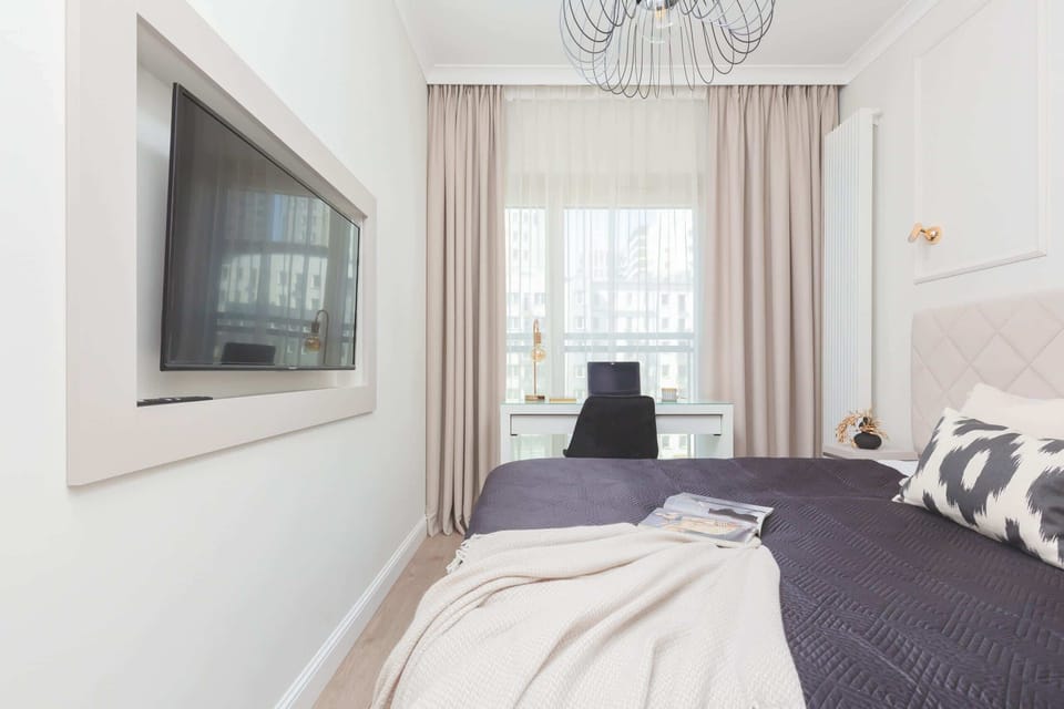 A bright, cosy bedroom with a double bed. A large flat-screen TV hangs on the wall to provide evening entertainment.