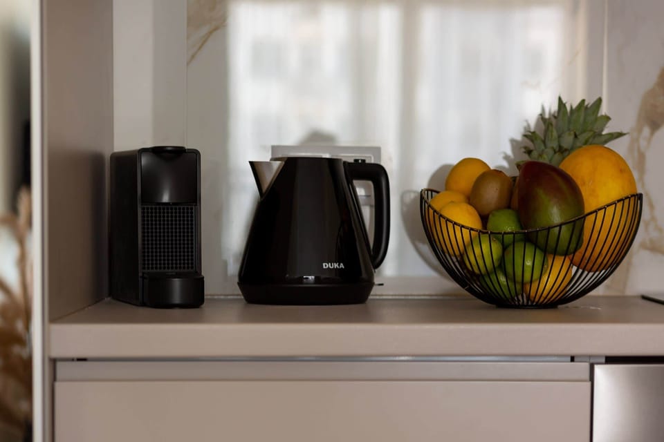 Close-up of a countertop with a coffee machine and electric kettle next to which is a fruit bowl.