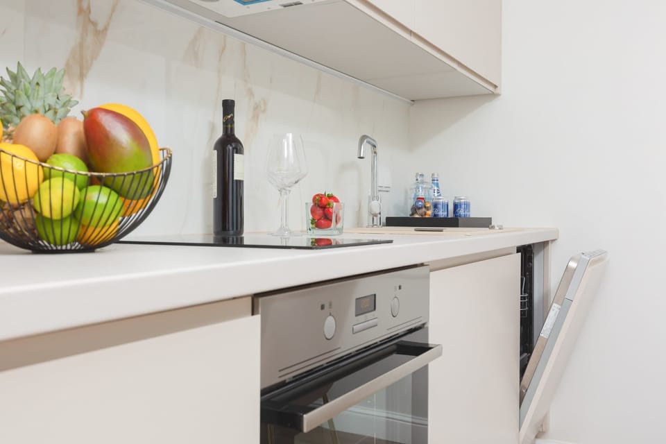 A sleek, modern kitchen with a white countertop, built-in appliances, and a fruit bowl with fresh produce. The kitchen design is clean and functional.