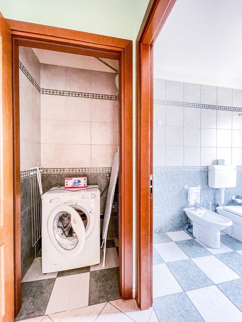 Room adjoining bathroom with washing machine and ironing board