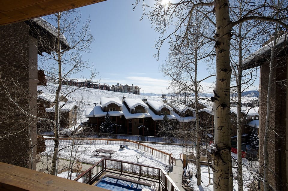 Breathtaking winter vista framed by aspen trees, showcasing snow-covered slopes and neighboring mountain lodges in this picturesque alpine setting.