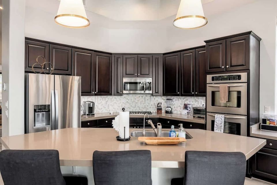 Your gourmet kitchen awaits with stainless steel appliances, dark wood cabinetry, and a spacious island perfect for meal prep and gathering with loved ones.