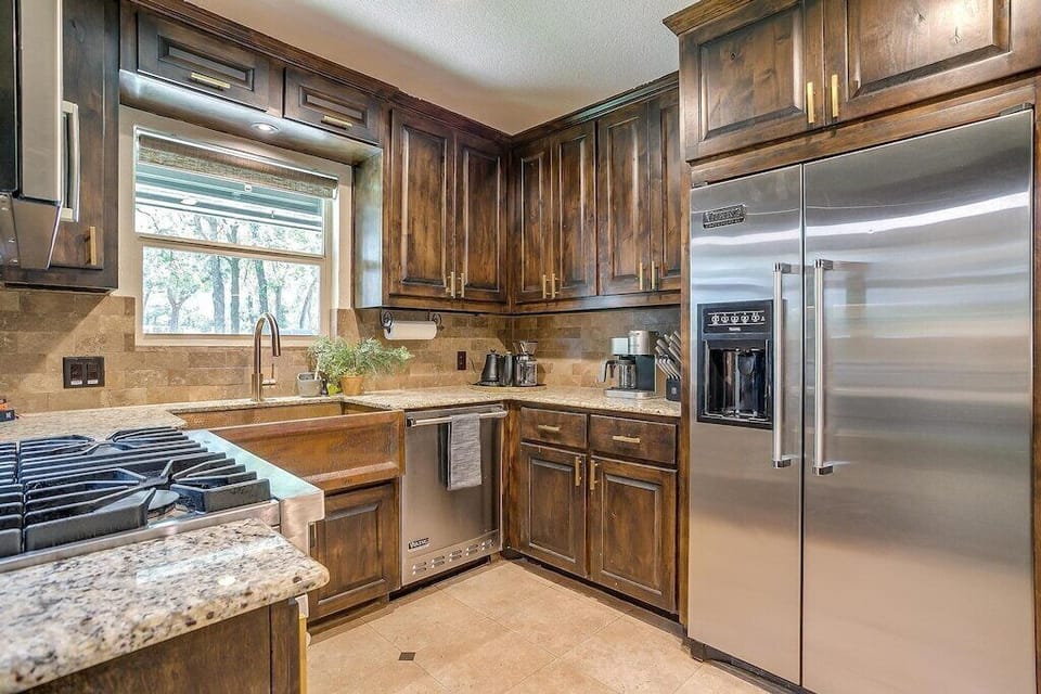 Full Viking kitchen with stainless appliances, farmhouse sink, granite counters, and dark wood cabinetry. A well-equipped vacation rental in Keller, Texas, built for groups who actually cook.