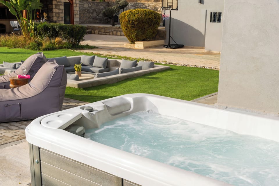 The heated spa whirlpool, next to a lounge area with tree shade. 