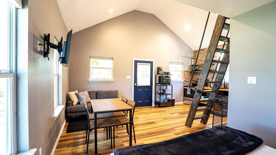 Open concept queen bed space, dining space & living space with vaulted loft. 