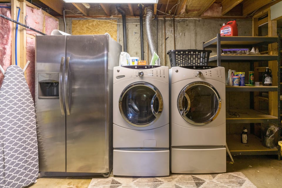 Laundry room with iron/ironing board, washer, dryer, and extra fridge for use 