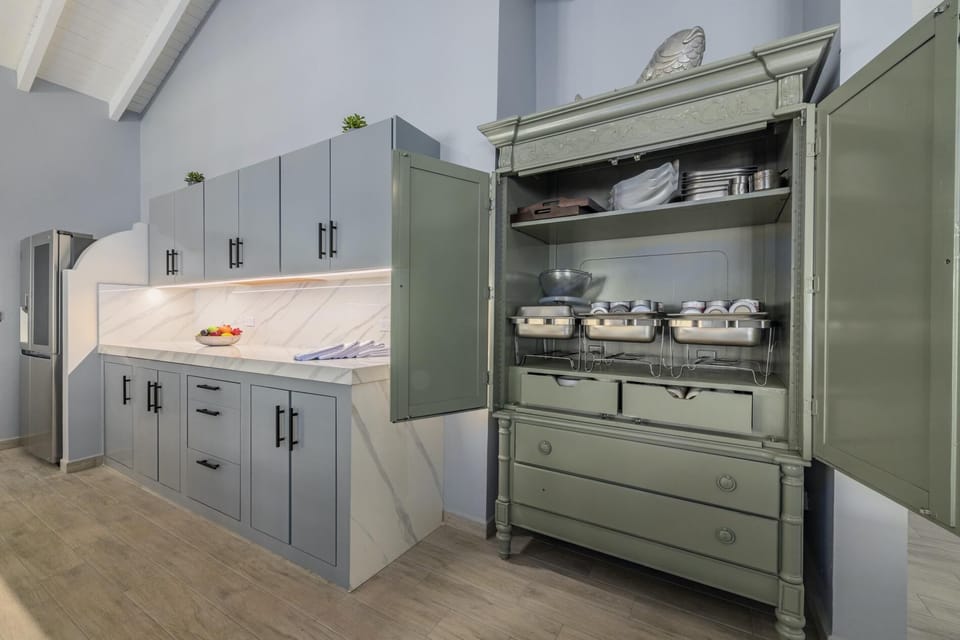This dining and kitchen area has an elegant color interior.  There is plenty of storage space in the full kitchen. There is an 8-seater table and cushioned chairs in the dining area.