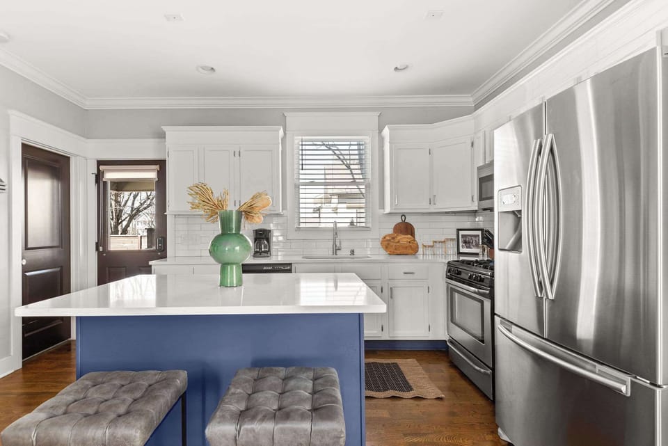 ️ Fully stocked kitchen! Prepare meals with ease using stainless steel appliances, white cabinets, and a spacious blue island. Coffee, creamer, and sugar provided. A back door leads outside for easy access! ✨