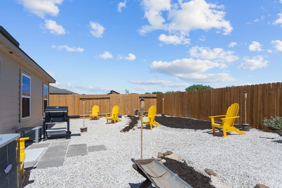 Unwind by the fire pit under the Texas sky with friends, enjoying comfortable seating and added privacy for a relaxed evening together.