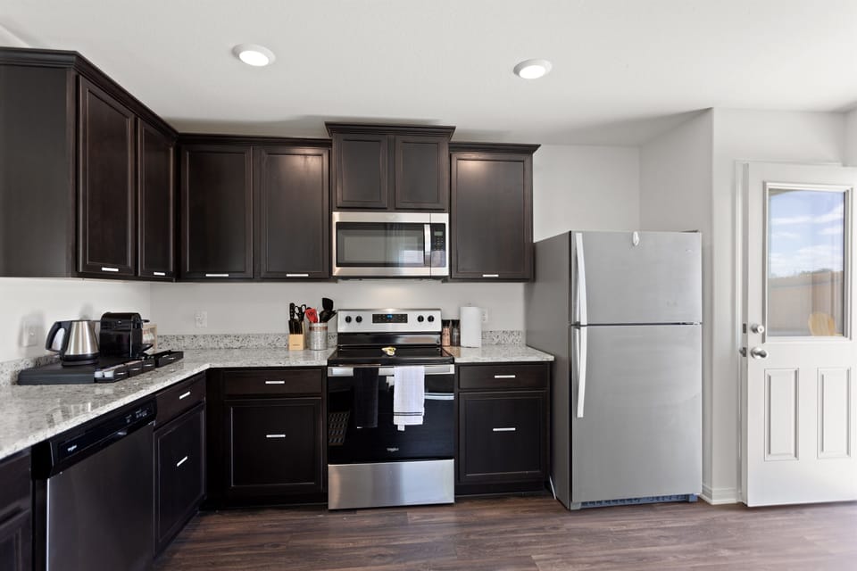 Fully equipped modern kitchen with stainless steel appliances, full size fridge, Keurig, cookware, and all the essentials you need to prepare meals with ease.