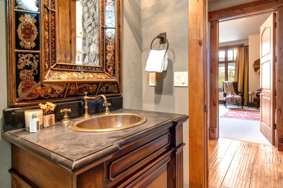 This elegant half bath features ornate wood accents, granite vanity, and mountain lodge flair.