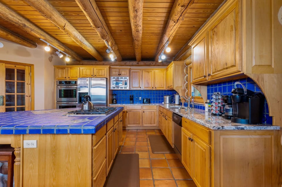Fully stocked kitchen with a blender, coffee pot, toaster, ice maker, double oven, microwave, pots, pans, dishes, utensils, and plenty of space to feed a crowd. 