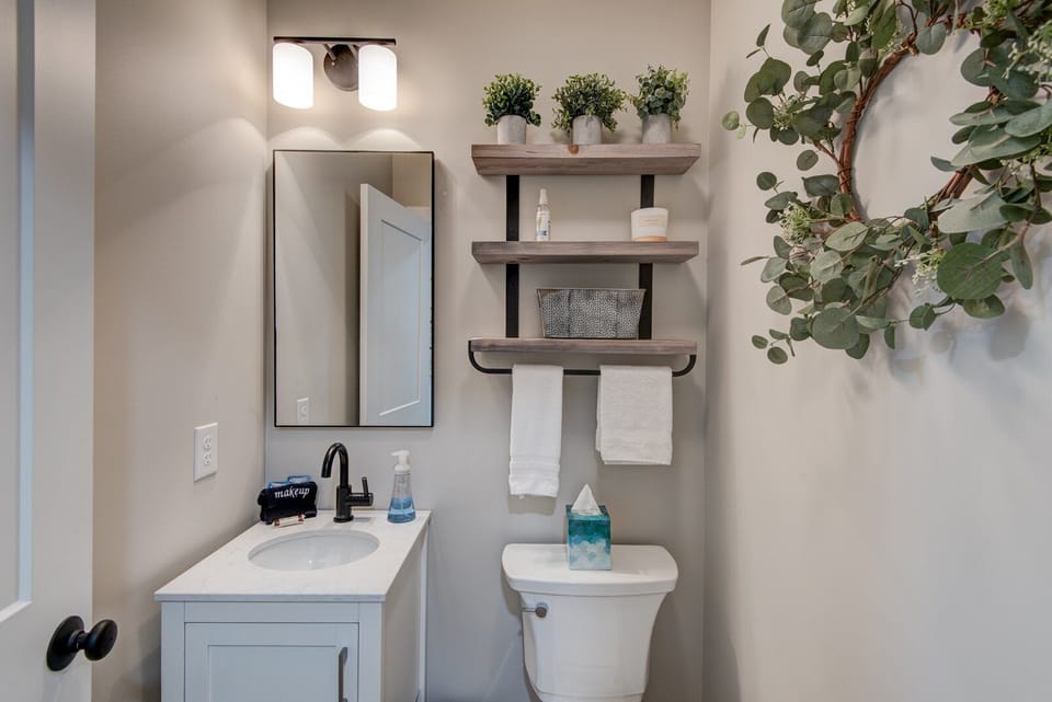 Charming half bath with rustic wood shelves and fresh greenery. Thoughtful touches make even the smallest spaces feel cozy at Lessons From Mars.