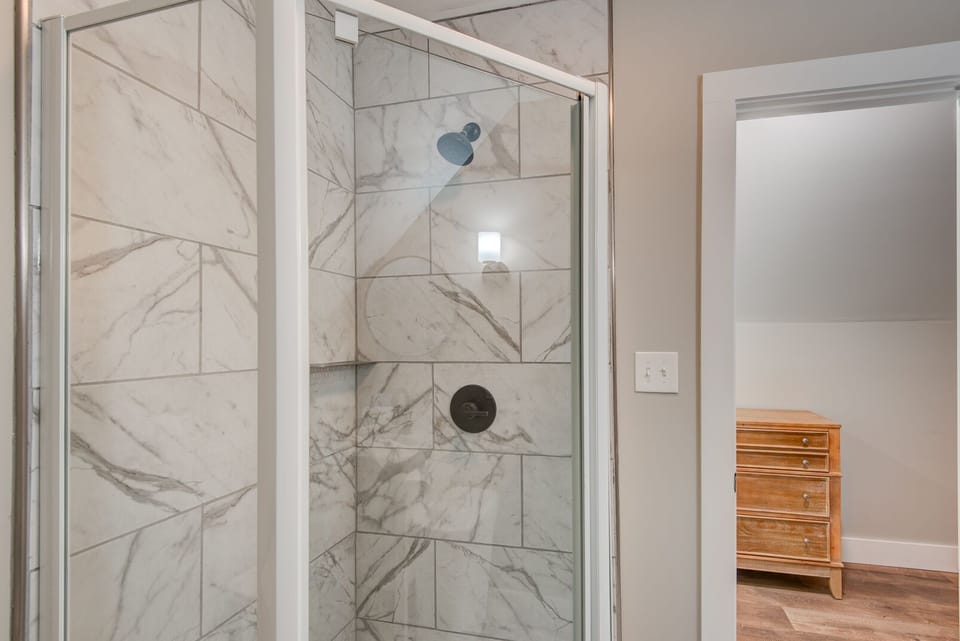 A spa-like walk-in shower with marble-look tile and matte black hardware. Clean, modern comfort waiting after a day on Beech Mountain.