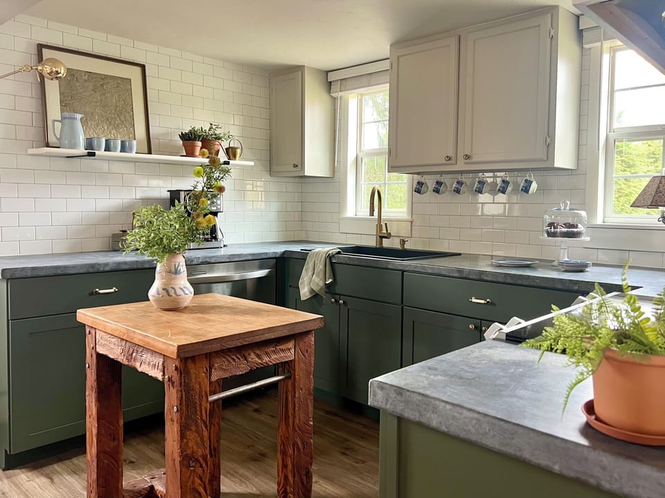 Custom zinc counters, antique rug, butcher block table and smokey green cabinets