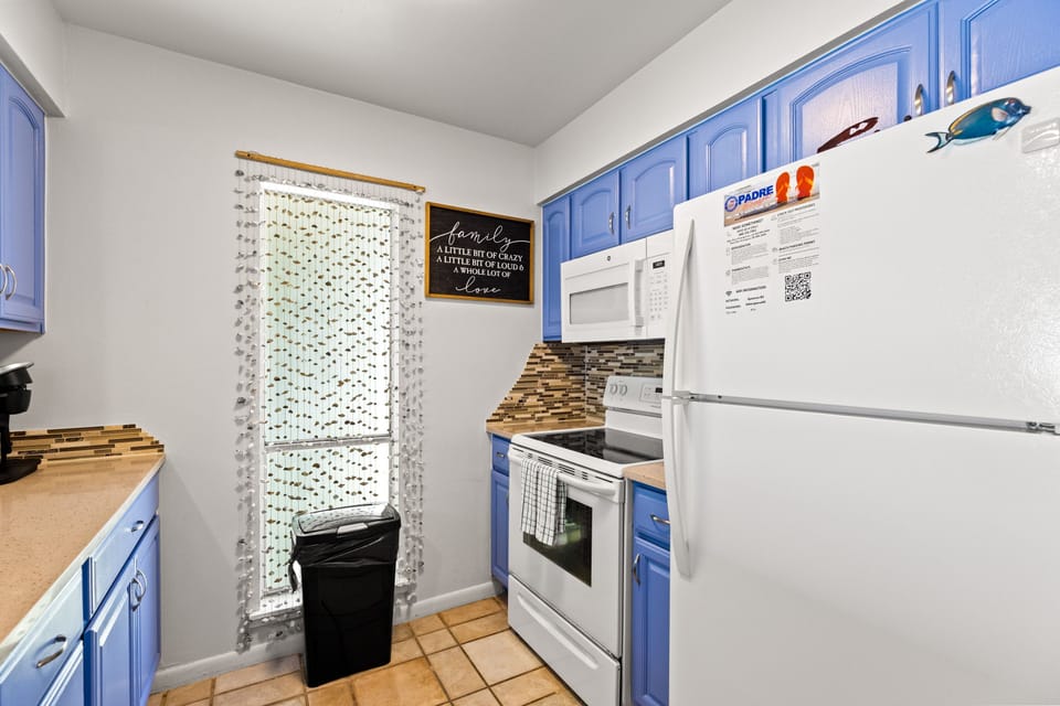 Your charming kitchen features vibrant blue cabinets, full appliances, and thoughtful touches that make cooking feel like home.