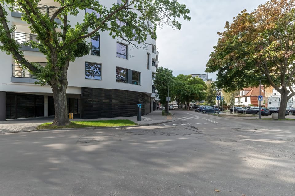 The exterior of the apartment building, surrounded by greenery and featuring a modern architectural design that blends with its surroundings.
