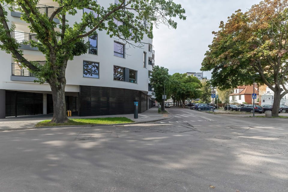 The exterior of the apartment building, surrounded by greenery and featuring a modern architectural design that blends with its surroundings.