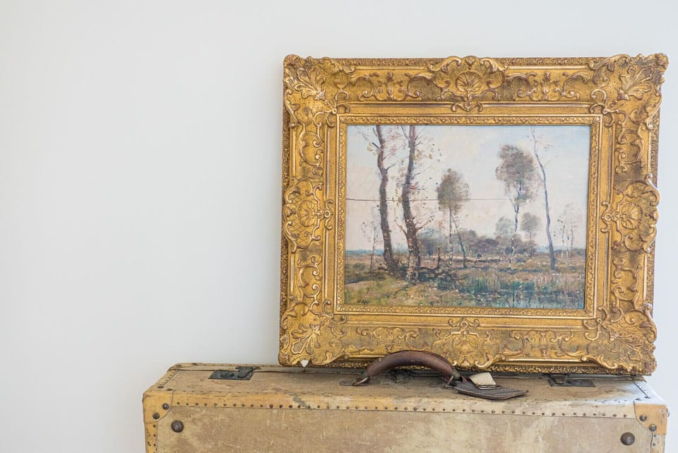 Ornate gold-framed landscape painting on vintage suitcase — Villa Jade, holiday villa in Sintra