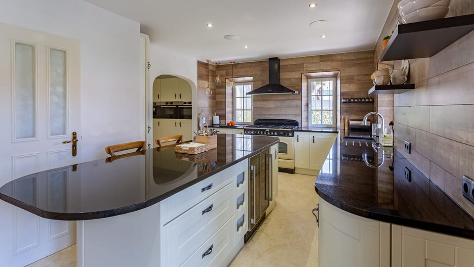 Kitchen island. Kitchen has large screen TV and musich system in ceiling.