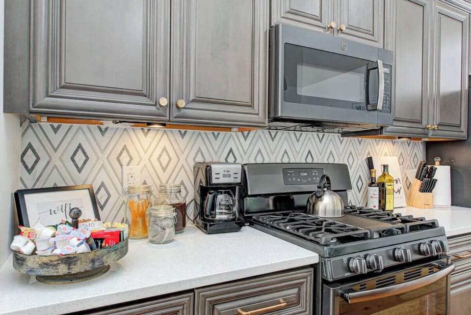 Mosaic marble backsplash and clean quartz counters in the kitchen for enjoyable meal prep.