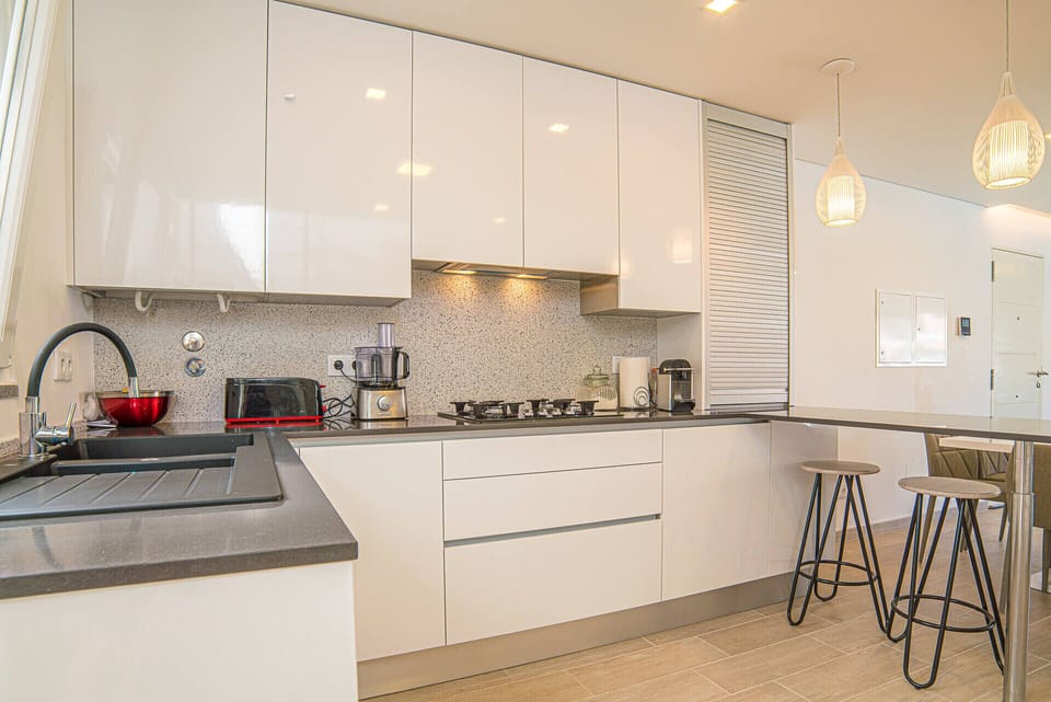 Modern white kitchen with dark countertops and pendant lights — Villa Santi, holiday villa in Aroeira