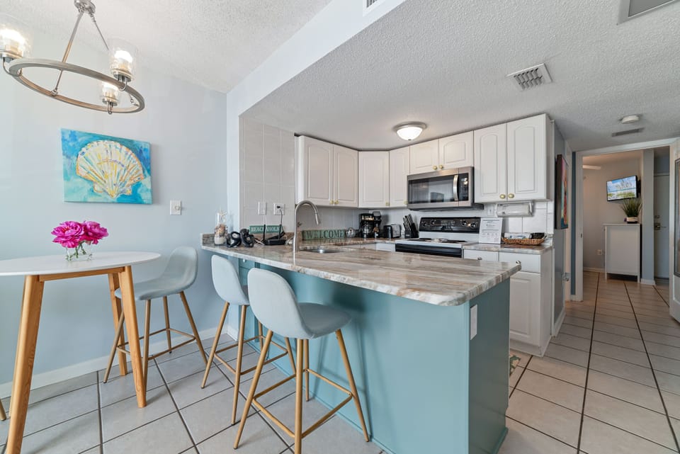 A coastal-inspired kitchen and dining area, featuring a clean, inviting aesthetic with soft blue accents and bright white cabinetry. The perfect spot to enjoy a morning coffee or a casual meal.