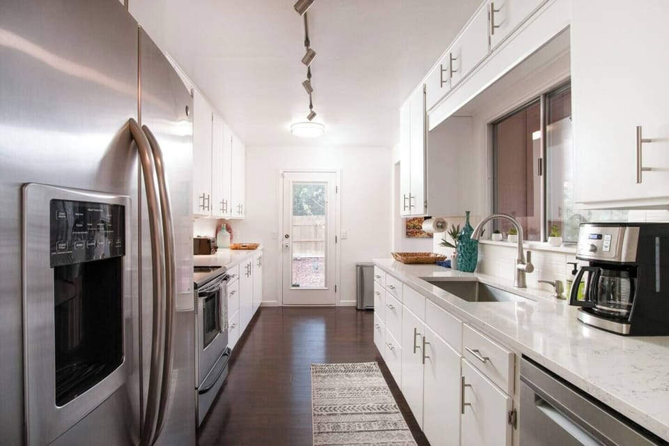 Modern galley kitchen with quartz countertops and stainless steel appliances.