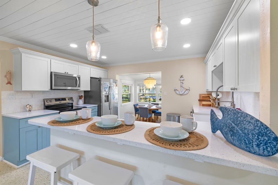 Bright, fully stocked coastal kitchen with bar seating, modern appliances, and an open layout perfect for morning coffee, casual meals, or gathering after a day on the water.