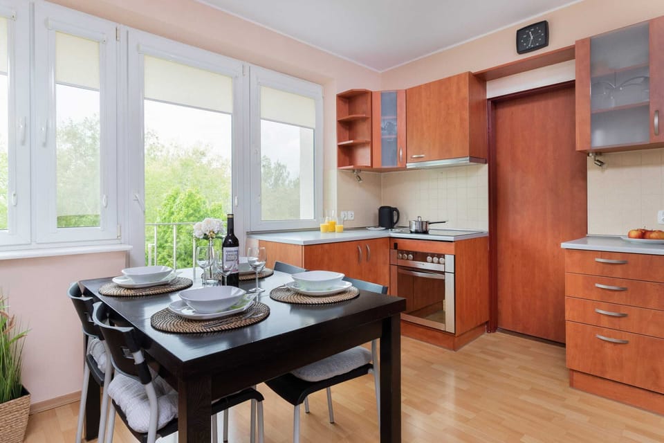 Kitchen and dining area with wooden cabinets, a dining table, and ample natural light.

