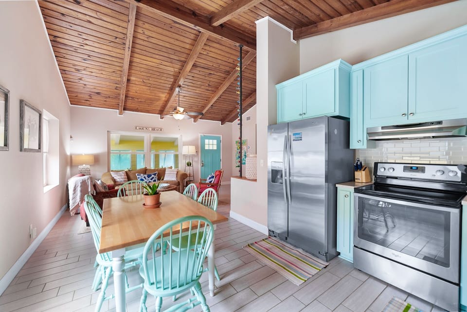 Gather around your spacious open-plan kitchen and dining area, where turquoise accents and warm wood beams create the perfect beach house atmosphere.