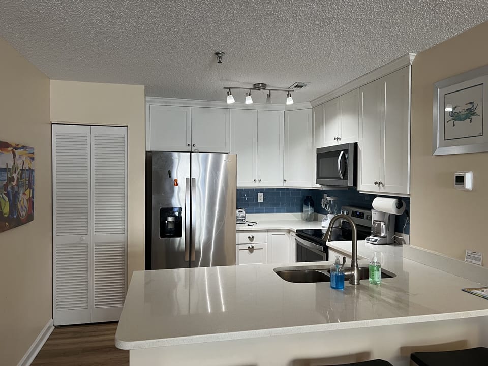 Kitchen has an open floor plan with a bar and 3 barstools open to dining area