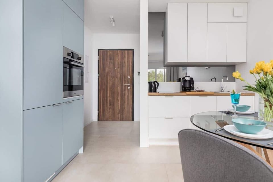A kitchen view with modern cabinets, a countertop, and flowers on the dining table. It combines style and functionality with a clean, minimalist design.