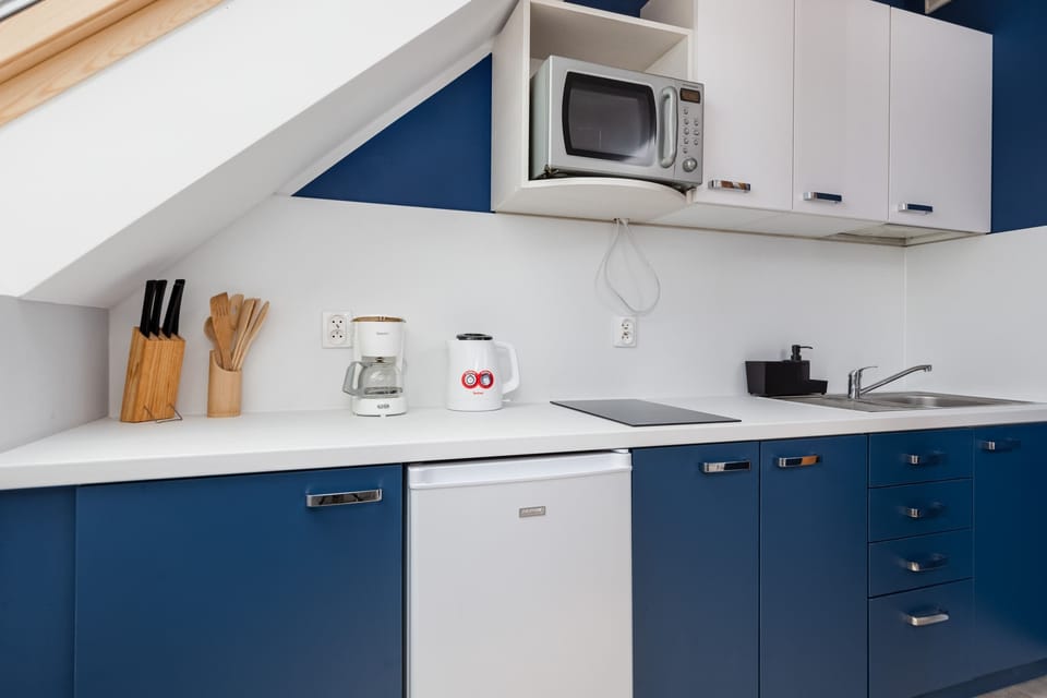 A kitchenette with a microwave, sink, and storage, designed for easy meal preparation.
