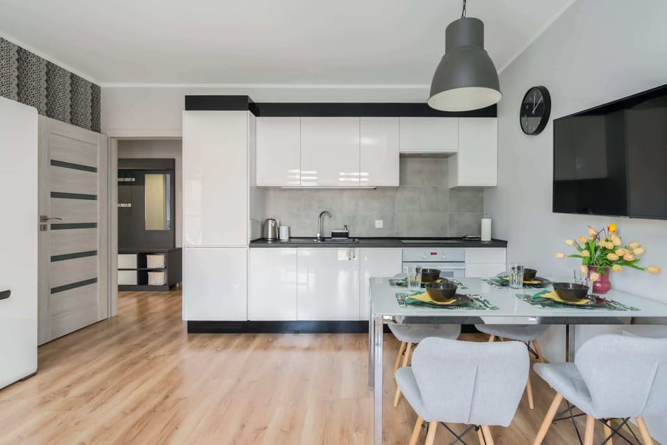 Open-plan kitchen and dining area with white cabinets, modern appliances, and wooden finishes.
