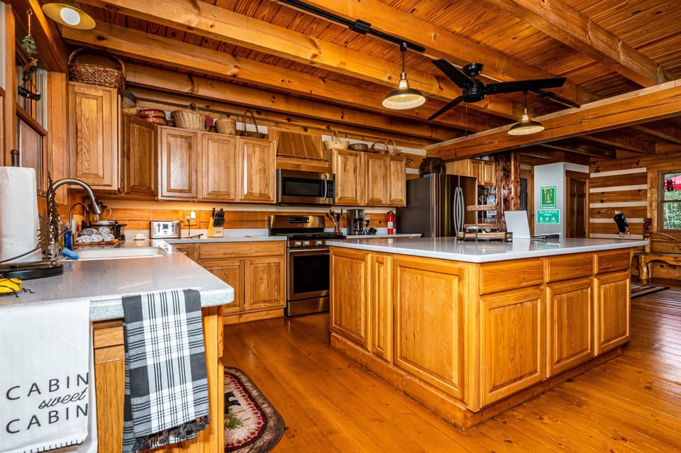 Spacious kitchen with honey oak cabinets, quartz countertops, stainless steel appliances, and exposed wood beam ceiling.