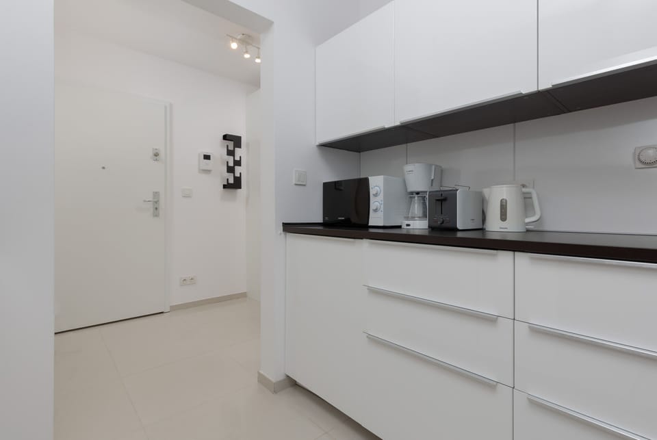 Kitchen view showcasing white cabinets, black accents, and ample natural light.
