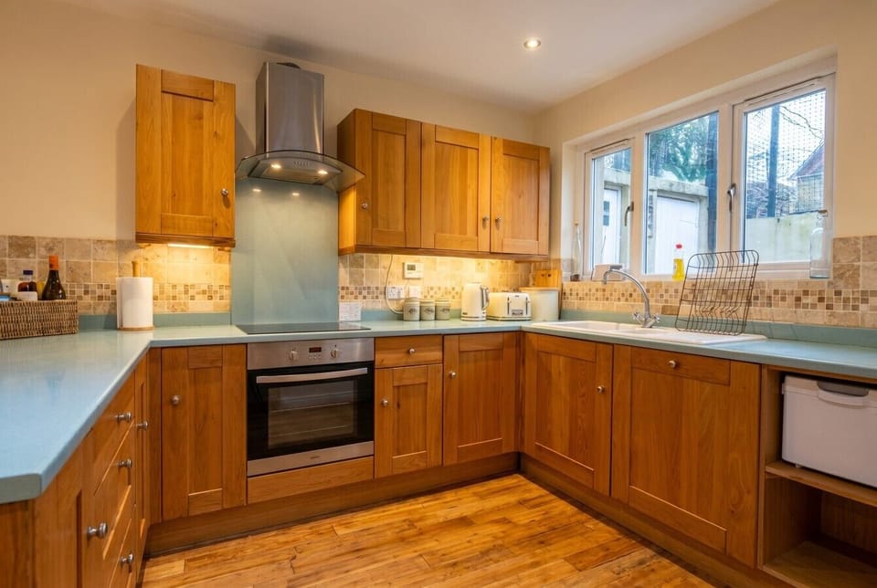 Smart oak kitchen with oven, ceramic hob and garden outlook.