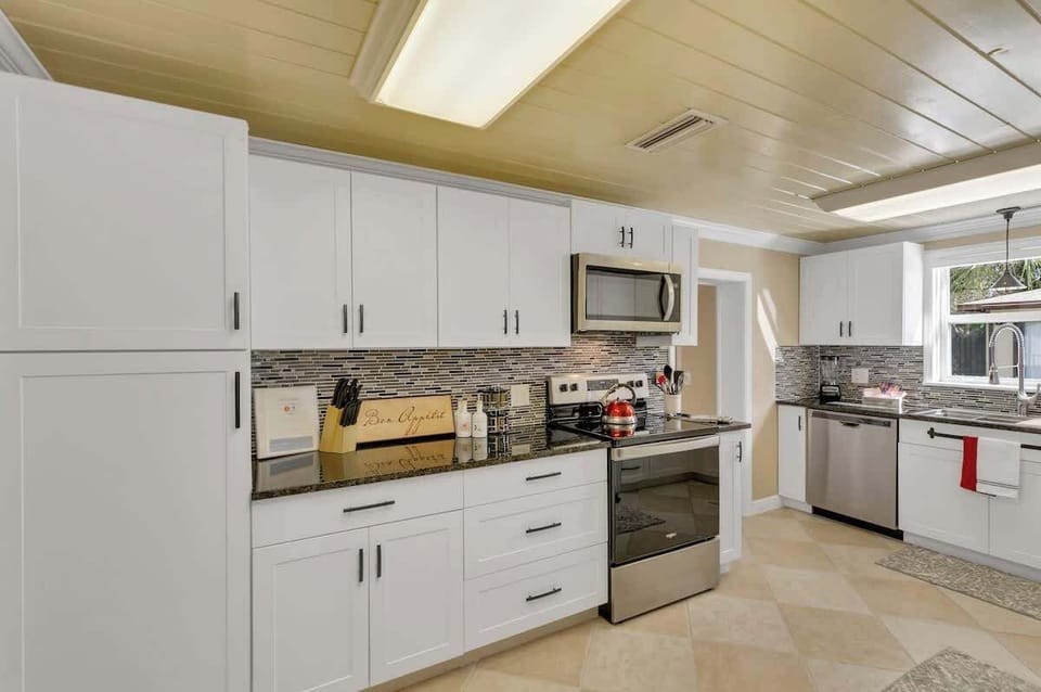 Open, clean & beautiful kitchen stocked with everything you should need: pots, pans, plates, bowls, glasses, cups, utensils, wine glasses, coffee mugs, tea kettle, Keurig Duo k-cup/coffee maker, k-cups, coffee, creamer, sugar blender, spice rack, etc