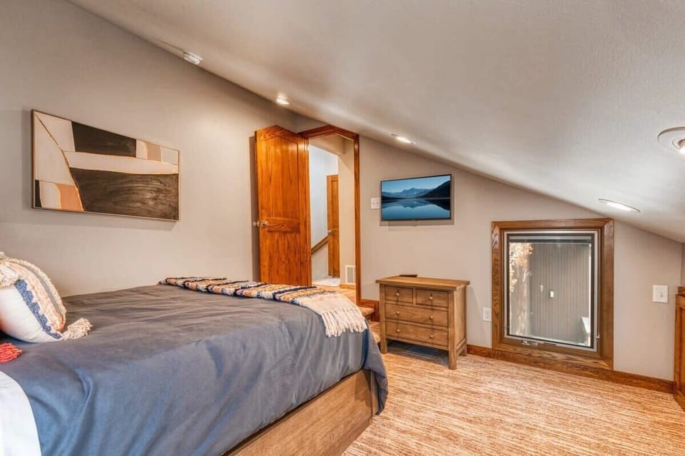 The second upstairs bedroom is a charming and restful space with a queen-size bed, nightstand, lamp, dresser and a flat-screen TV where you can relax and unwind before drifting off to sleep.