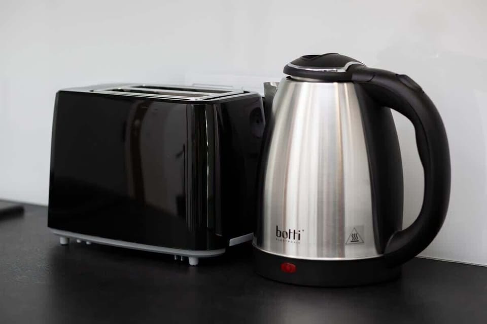 A close-up of a black kettle and toaster on the kitchen counter, highlighting practical amenities for guests.