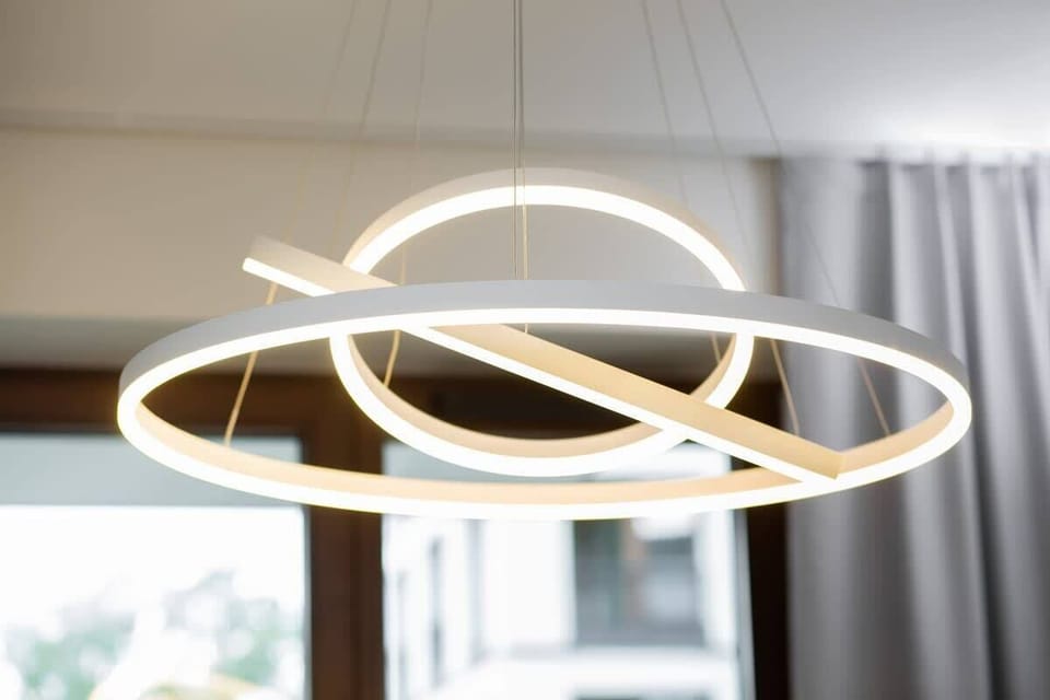 A close-up of a designer ceiling lamp with a geometric circular shape in gold and white finishes.