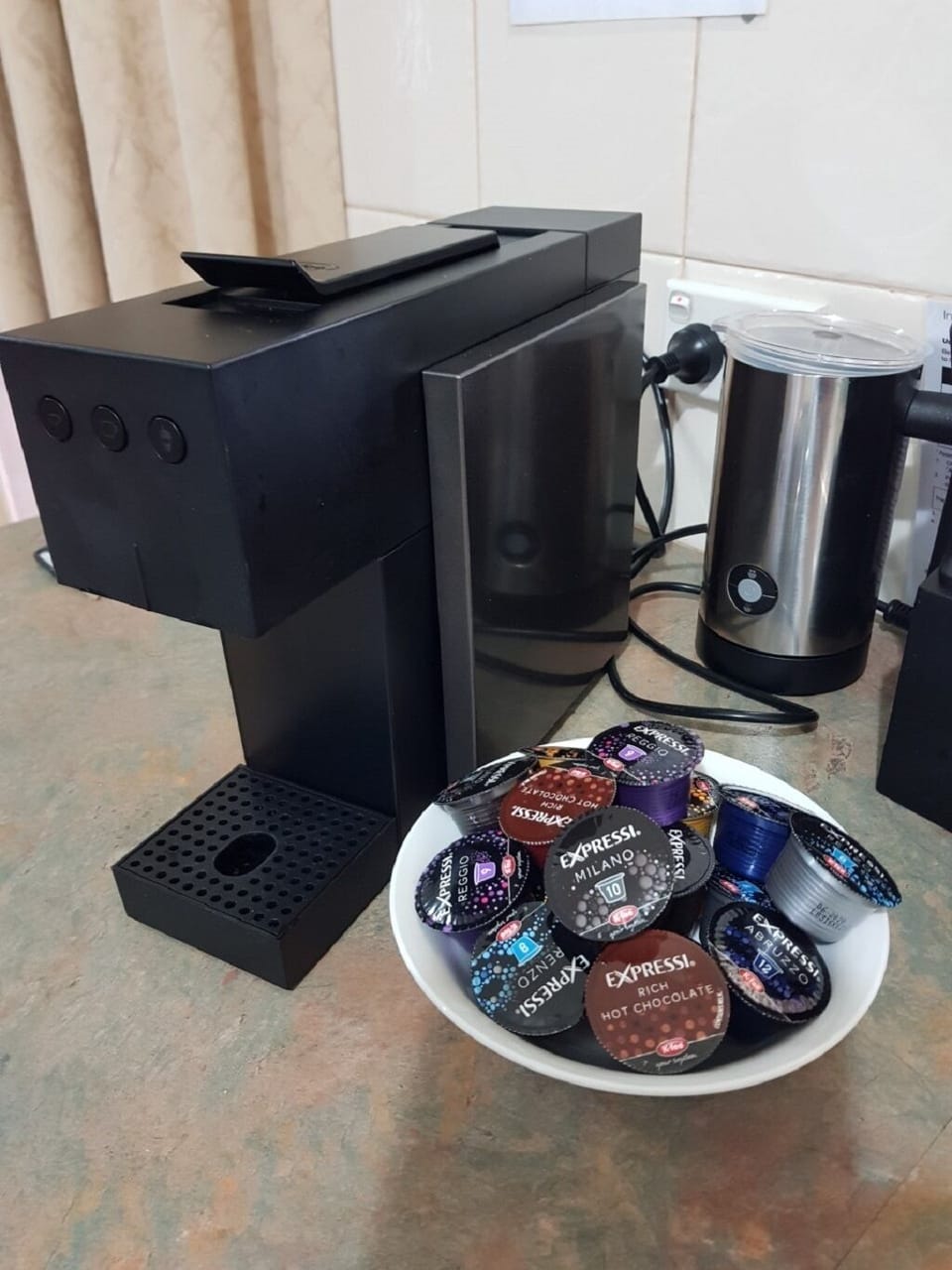 Coffee pod machine with milk frother and a selection of coffee pods.