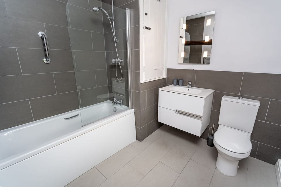 The modern bathroom is found on the 1st floor and features a bath with overhead shower