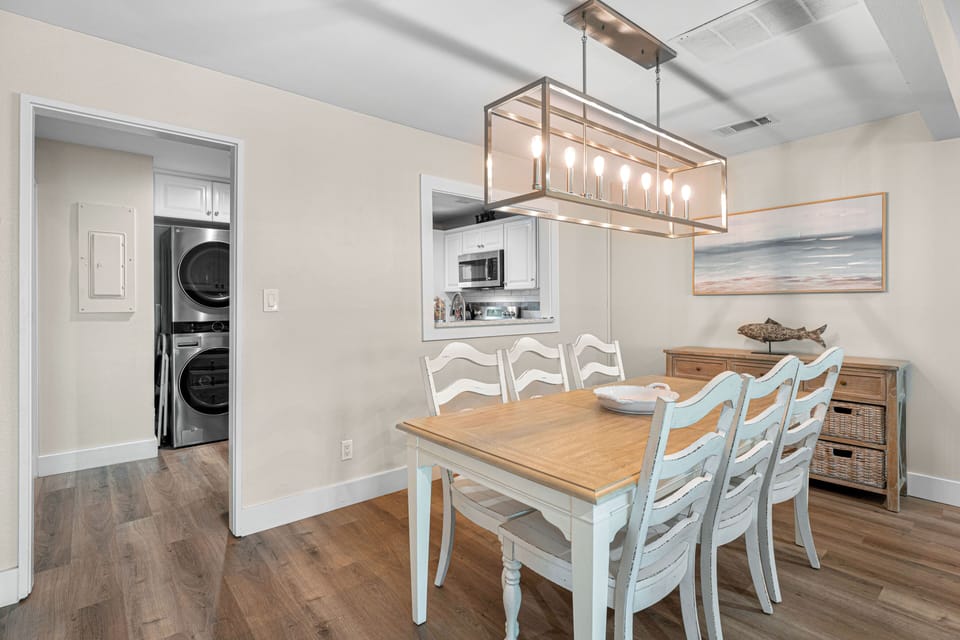 This inviting dining space features seating for six, a coastal wood table, and a contemporary chandelier