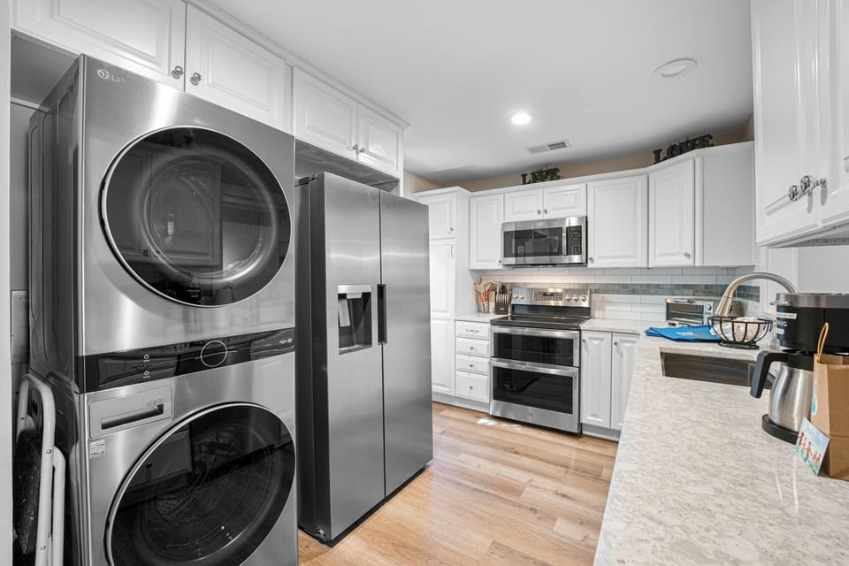 A beautifully updated kitchen featuring stainless steel appliances, quartz countertops, and ample cabinetry—complete with an in-home washer and dryer for added convenience.