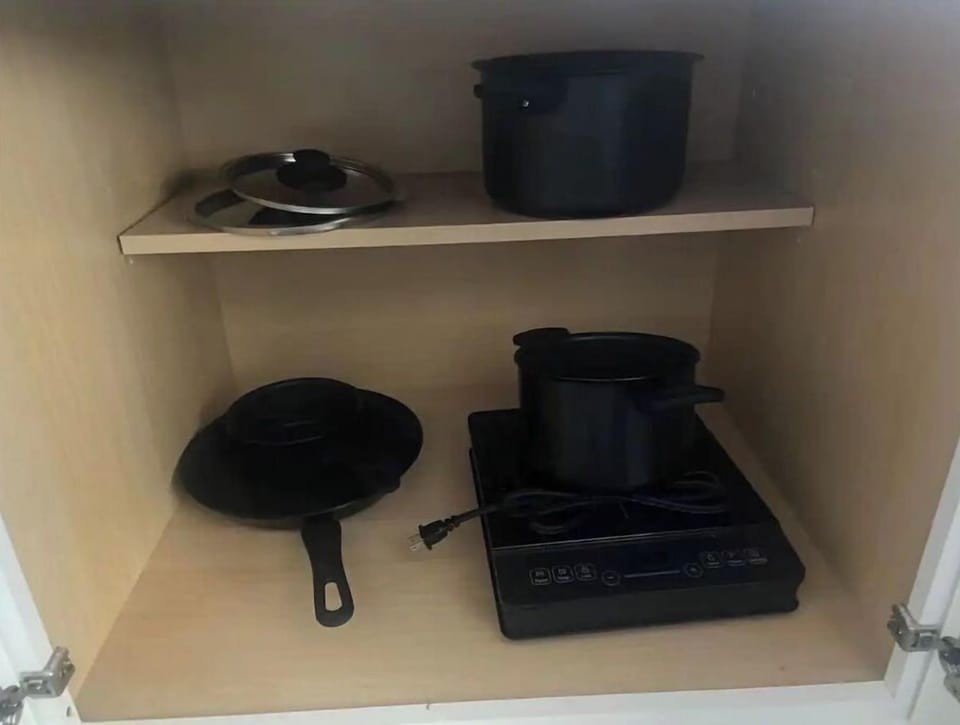 Pots and pans, and an electric hotplate can be found inside the cabinets.