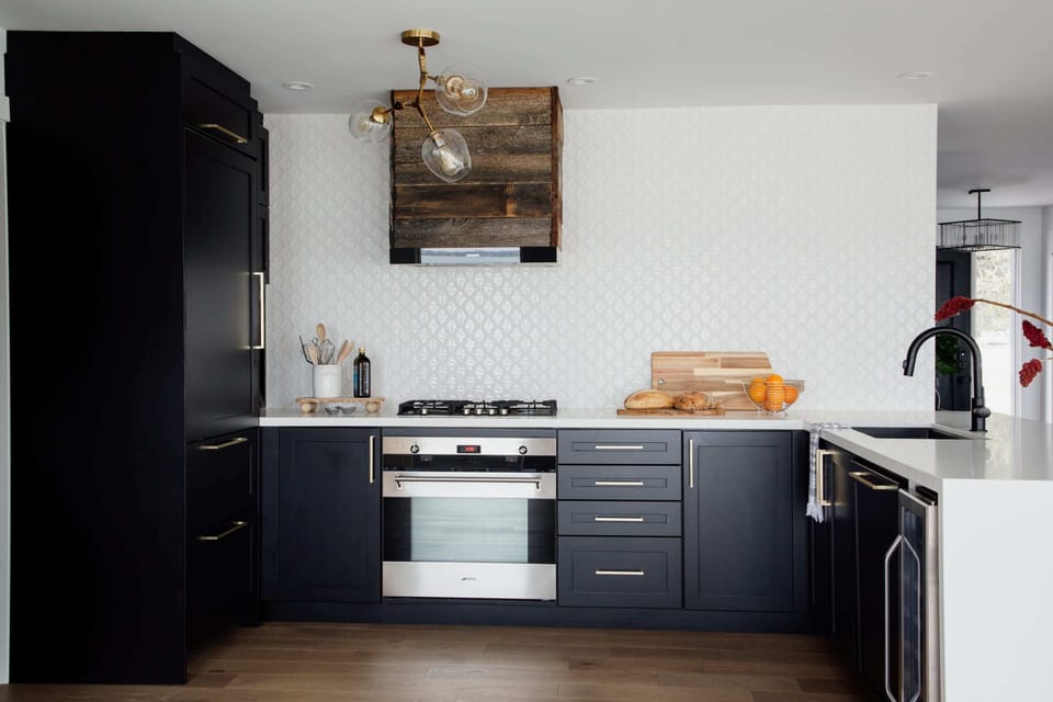 A stunning moody kitchen with a custom barn board range hood and counter to ceiling tiled wall.