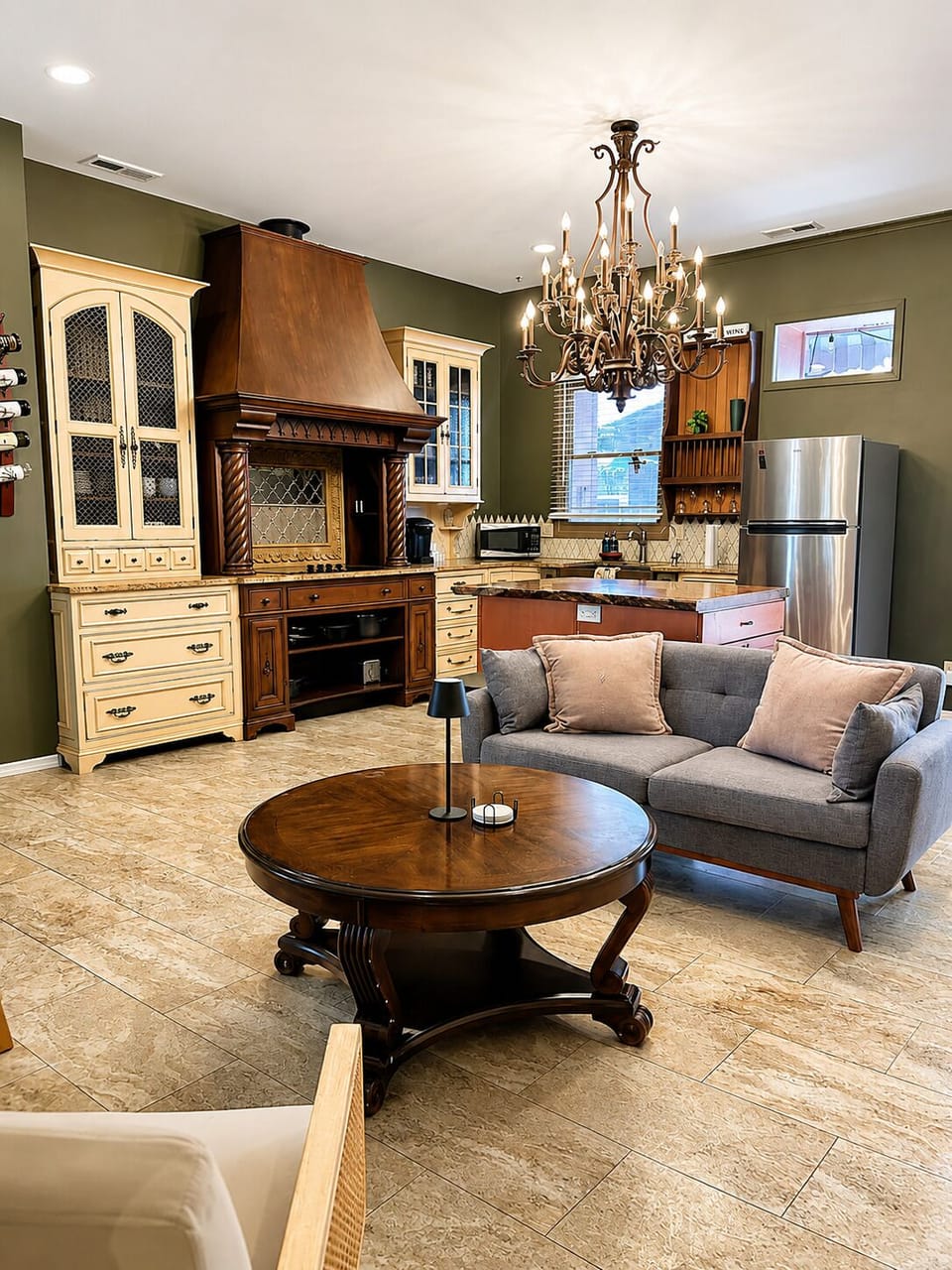 A second angle highlights the ornate cabinetry, fireplace, island, and lounge seating in the open main room.